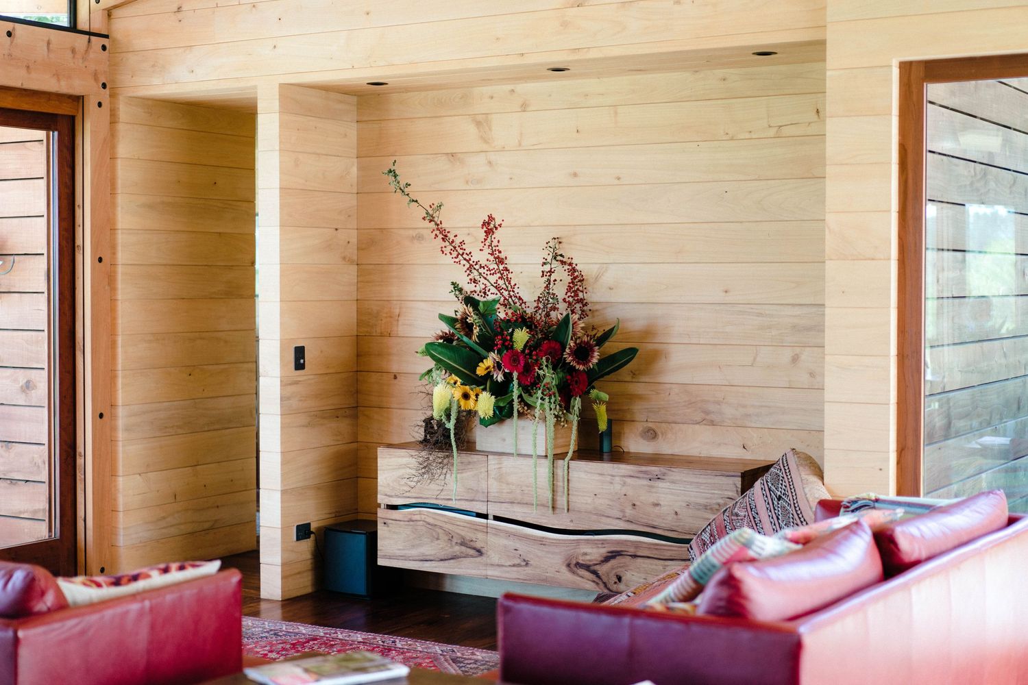 Modern rustic interior space with pink couches and natural wood paneled walls.