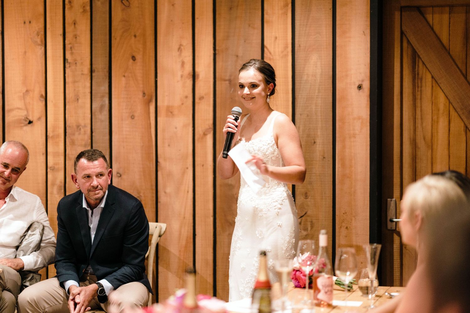 Person speaking during wedding reception in rustic wooden venue.