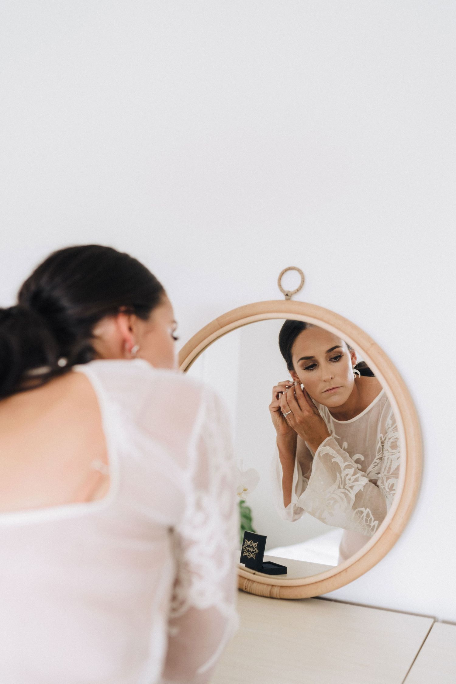 Elegant bridal reflections in a round mirror during wedding day preparations.