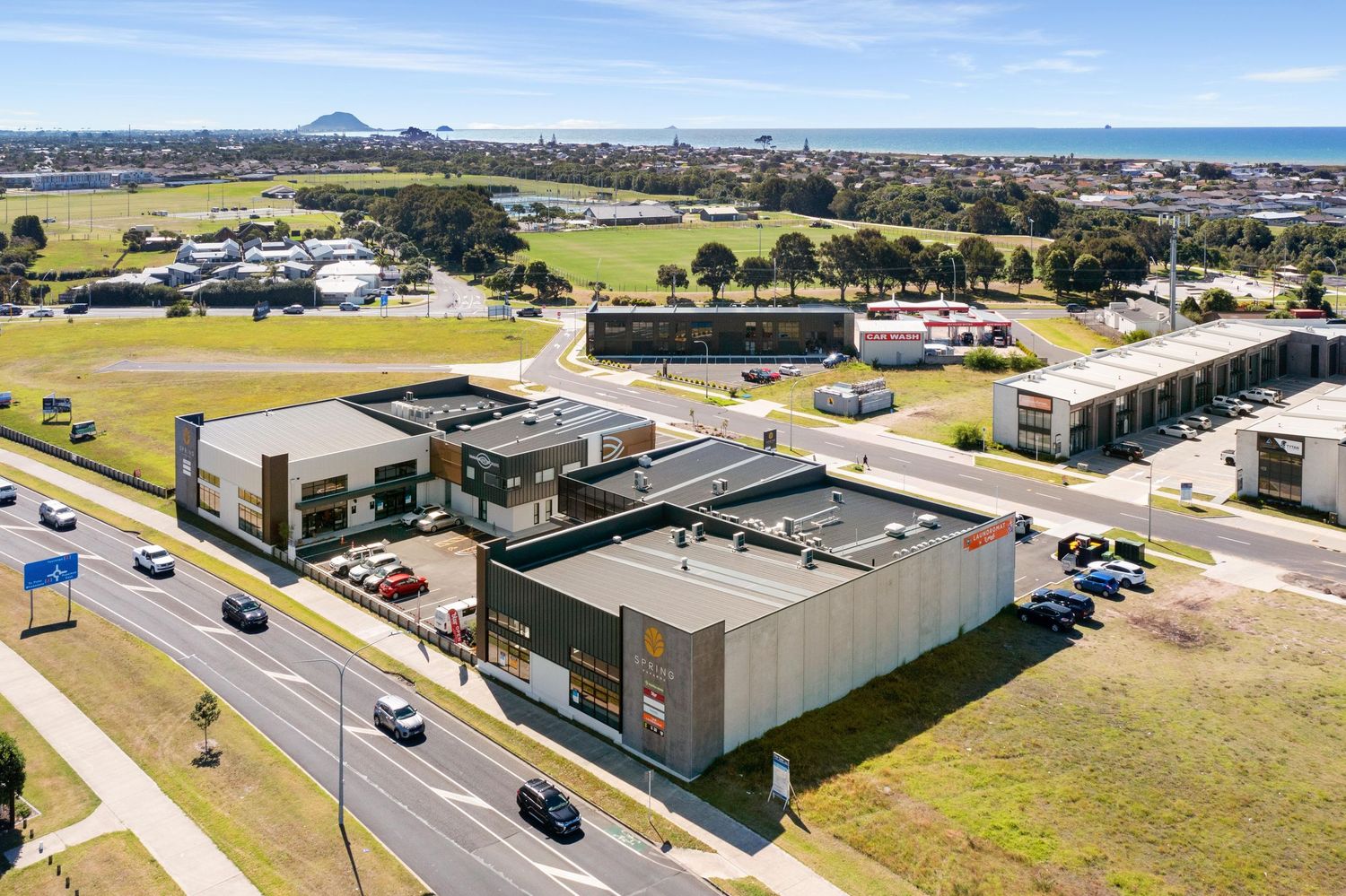 Aerial view of a modern commercial retail complex with parking lots and surrounding buildings.