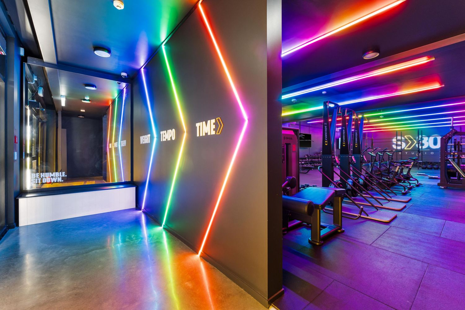 Modern fitness gym interior with vibrant neon lighting and exercise equipment in a contemporary workout space.