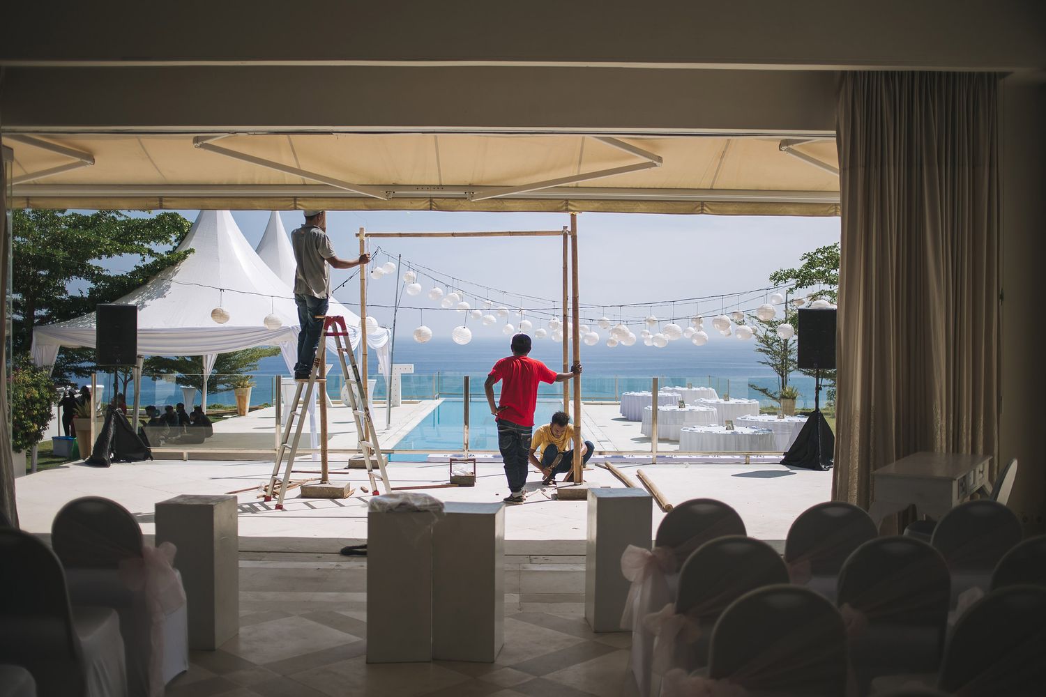 Event crew setting up stage or equipment on outdoor terrace overlooking ocean view.