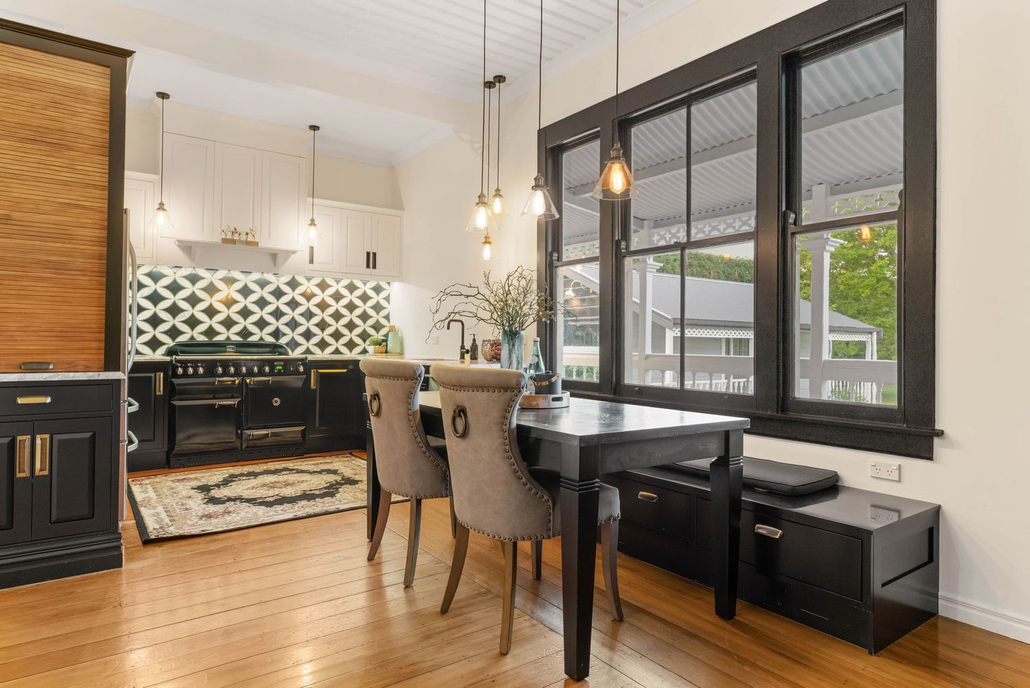 Modern dining area with black built-ins, wood floors, pendant lights and geometric wall pattern.