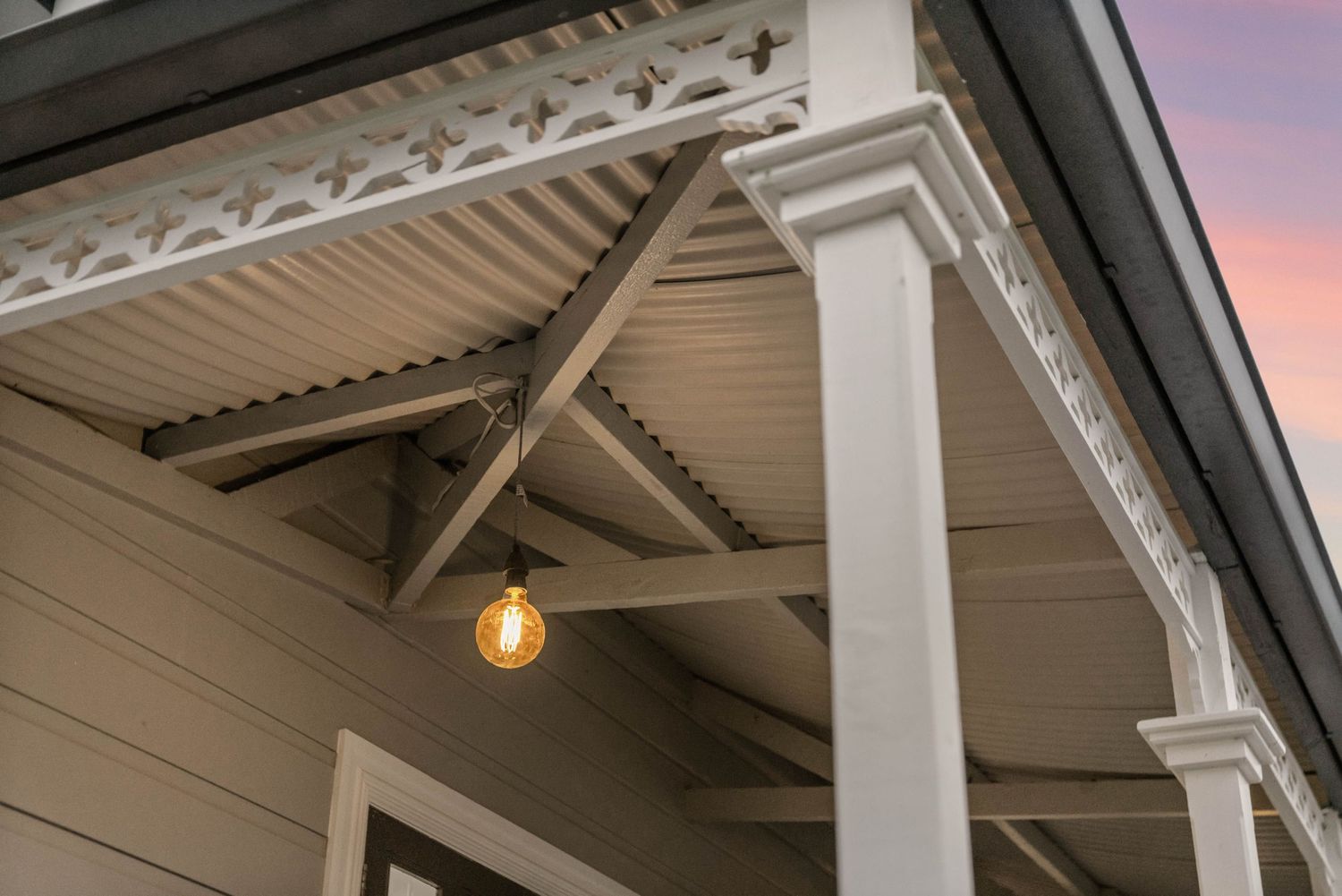 White outdoor patio ceiling with exposed beams and pendant light fixtures creating an elegant covered space.