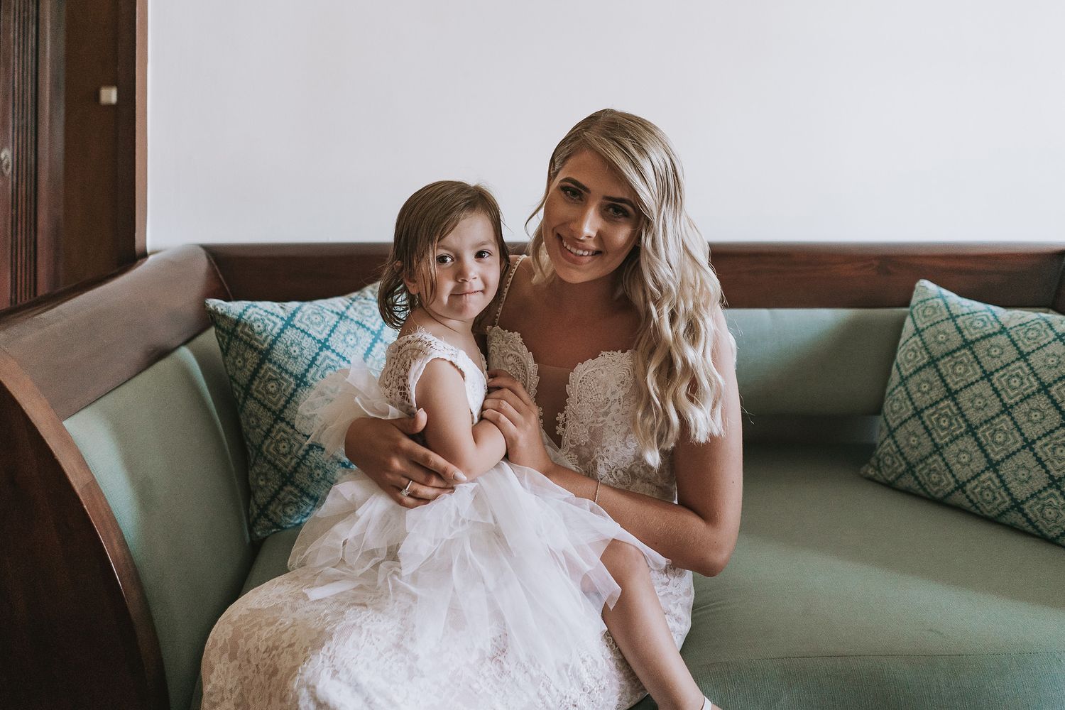 A tender moment shared on a mint green couch in formal attire.