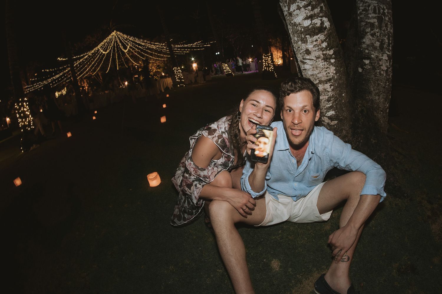 Candid evening celebration moment under string lights at outdoor wedding reception.