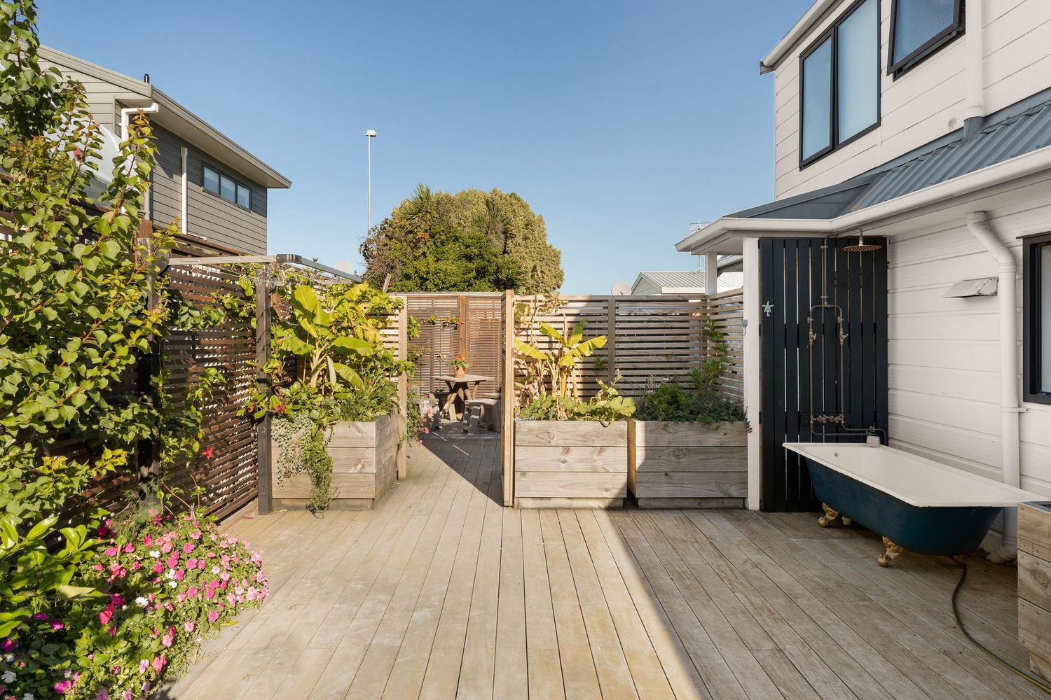 Modern white house exterior with wooden deck and glass doors under clear blue sky.