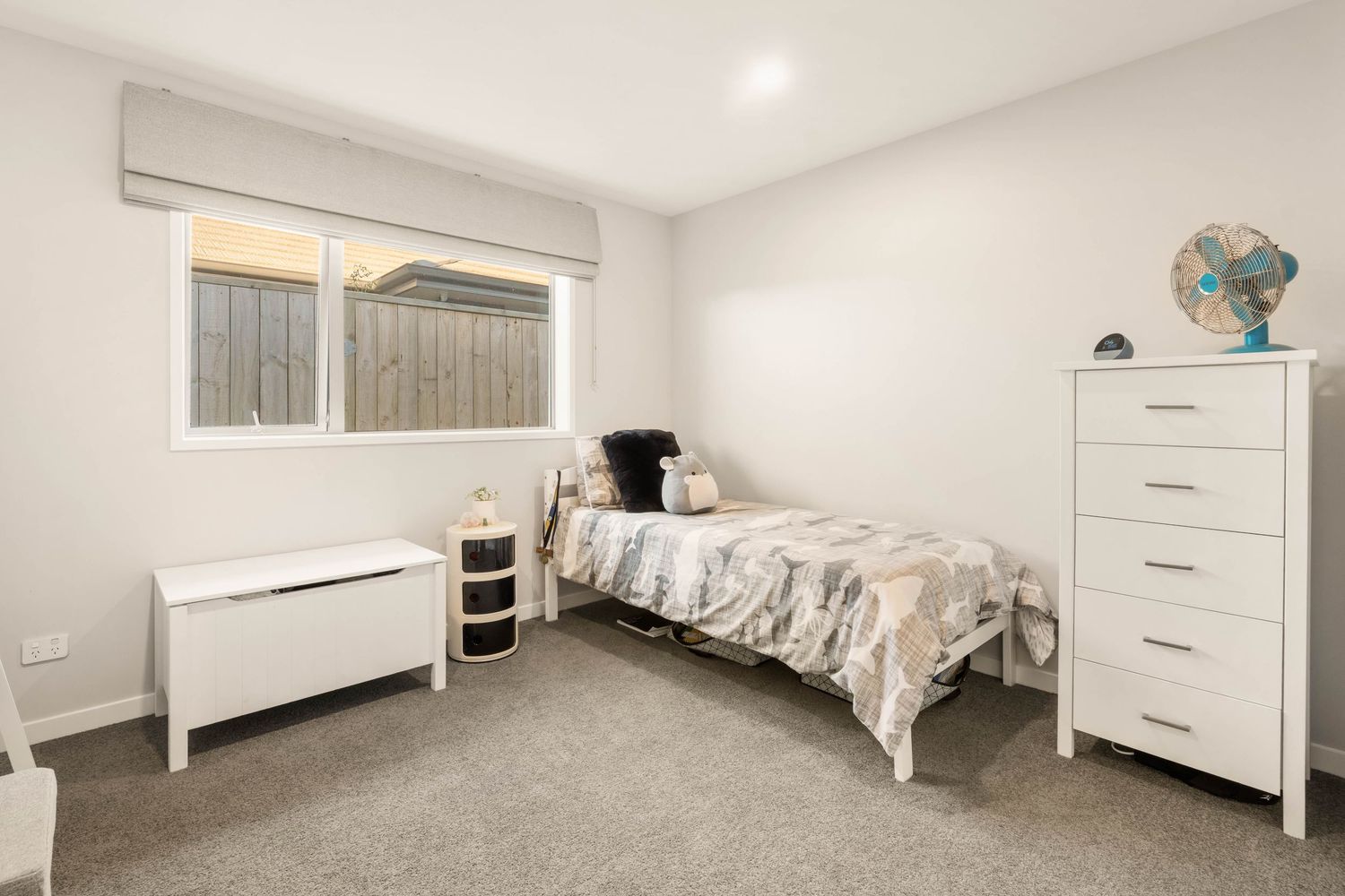 Spacious bedroom with white furniture, storage drawers and natural lighting.