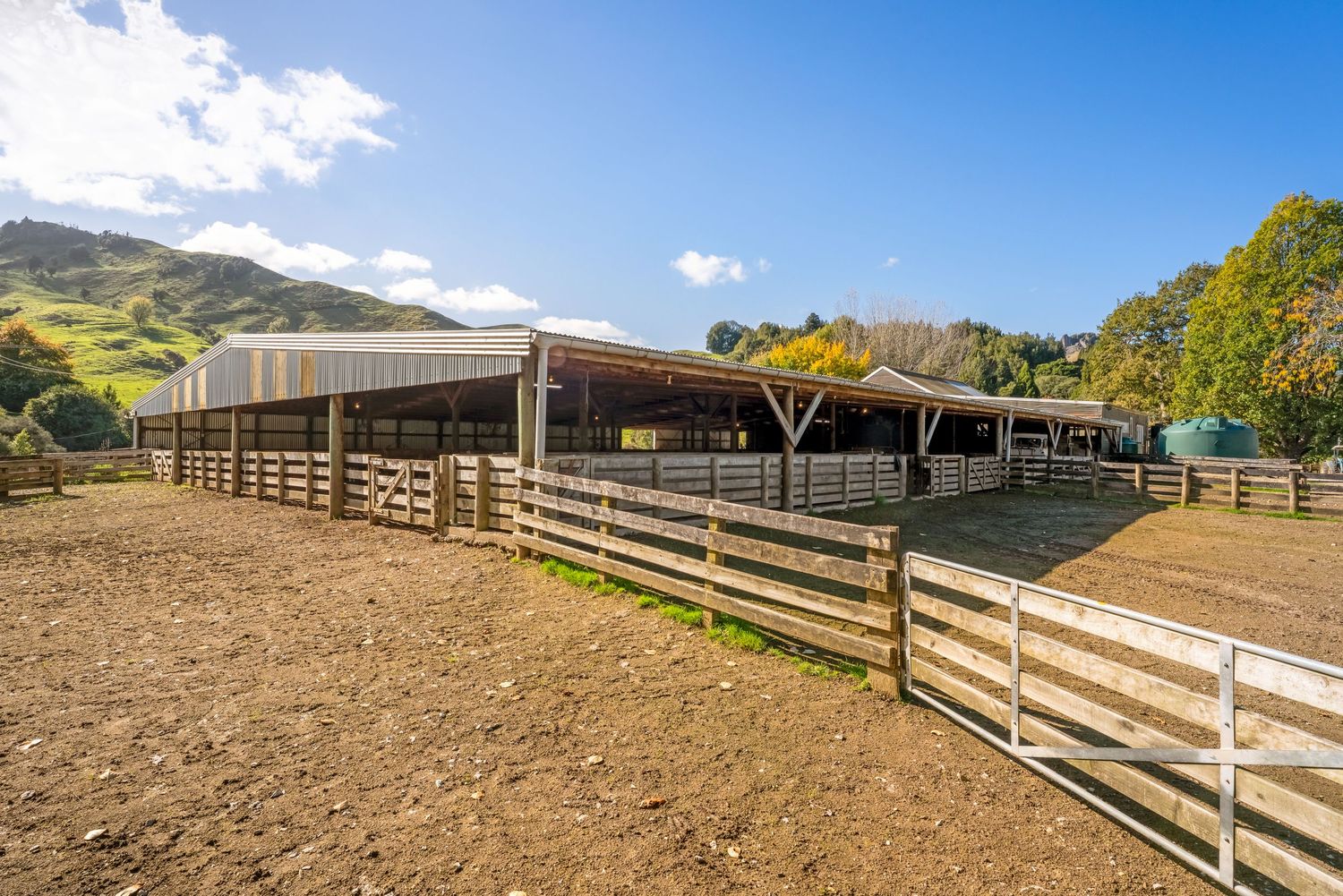 Rustic wooden horse paddocks and fencing on a gently sloping hillside pasture.