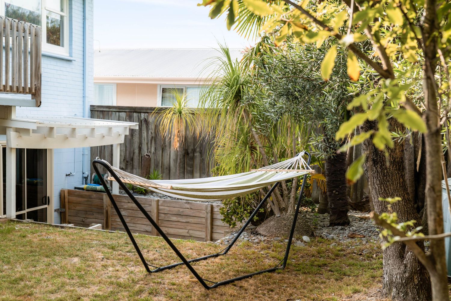Backyard hammock setup between palm trees with tropical landscaping.