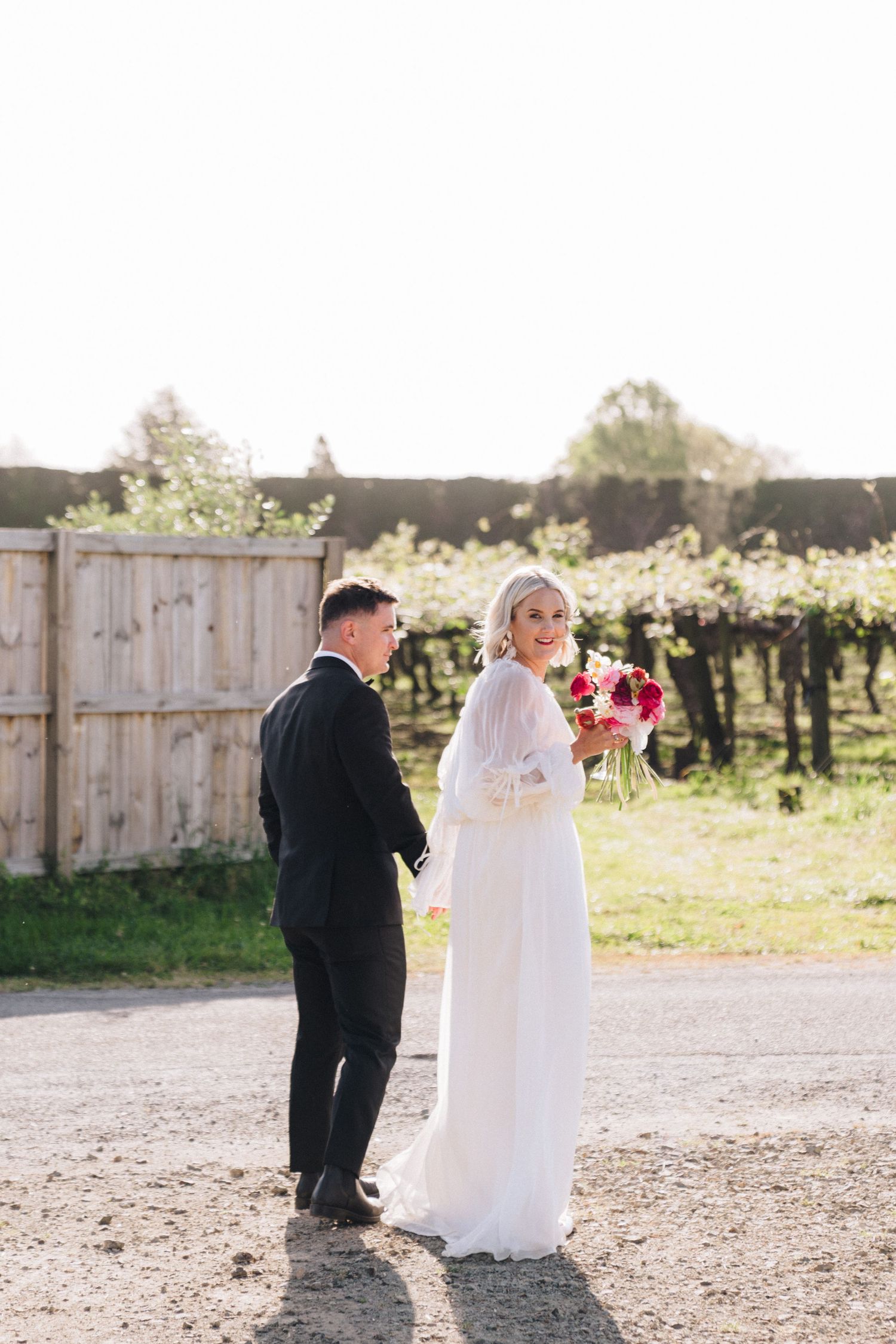 Bride and groom share a quiet moment together on a rustic farm path.