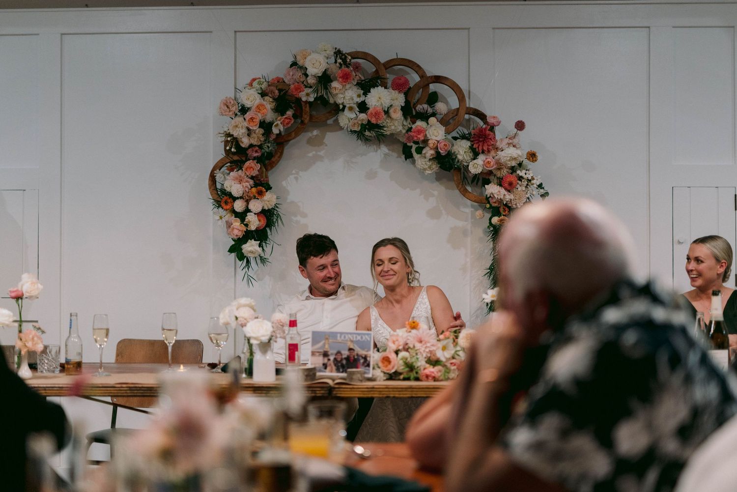 Wedding reception dining tables decorated with pink floral arrangements and candles.