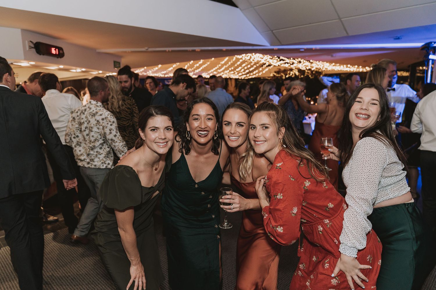 A lively crowd of people dancing and socializing at what appears to be an indoor celebration or party venue.