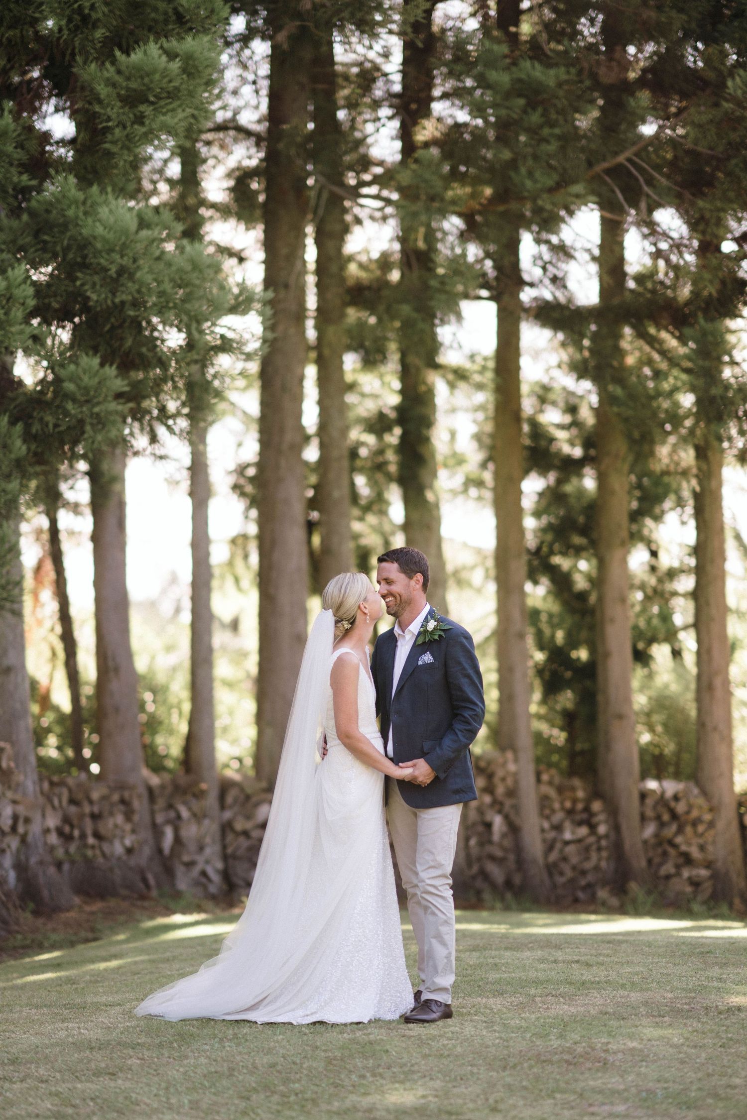 Outdoor wedding photography in a serene forest setting with tall pine trees and sunlight filtering through.