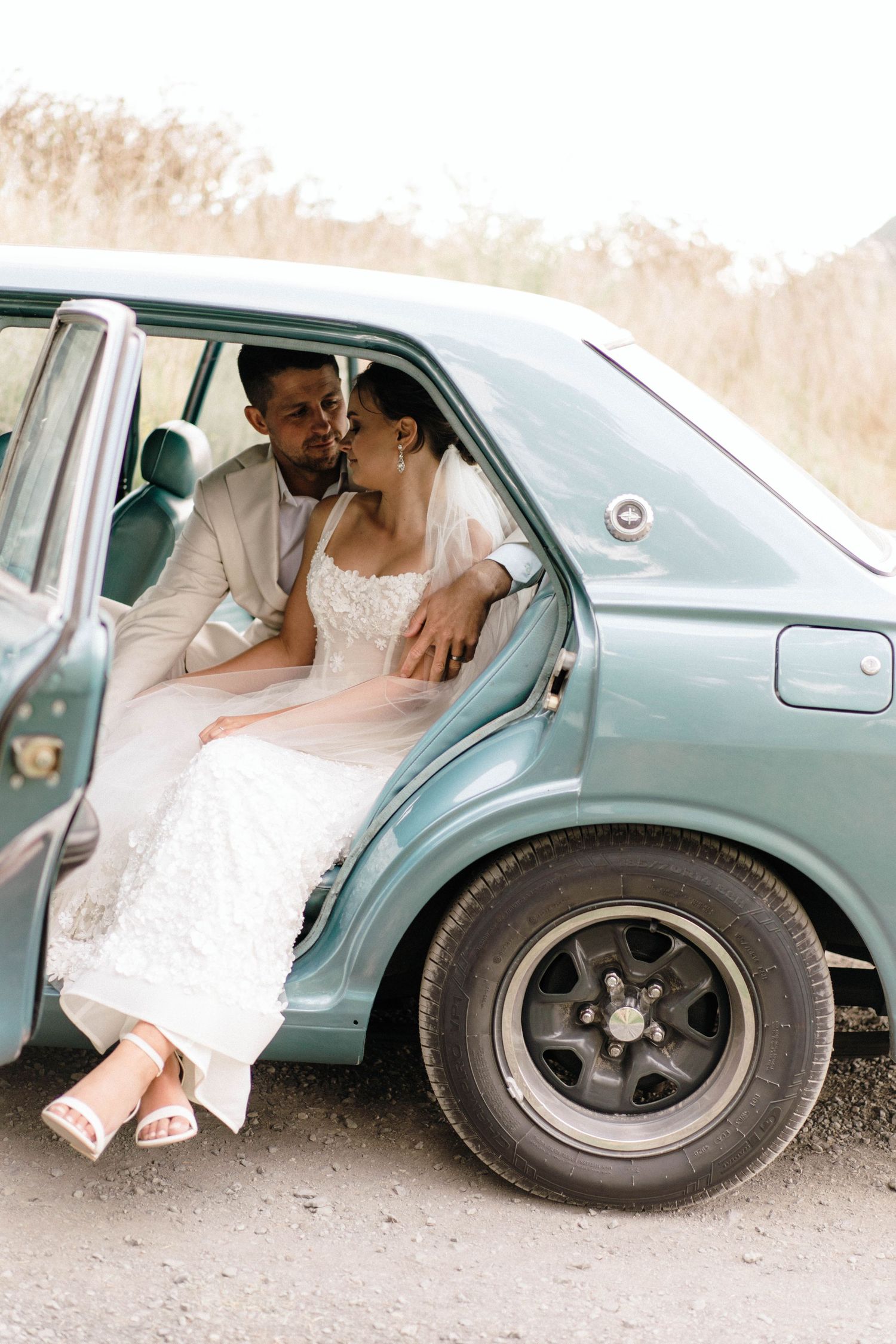 Couple sharing an intimate moment in a vintage blue car.