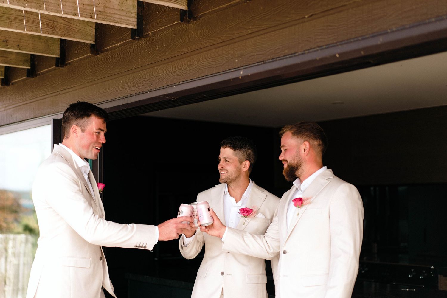 Group in white formal attire sharing drinks on an outdoor terrace.