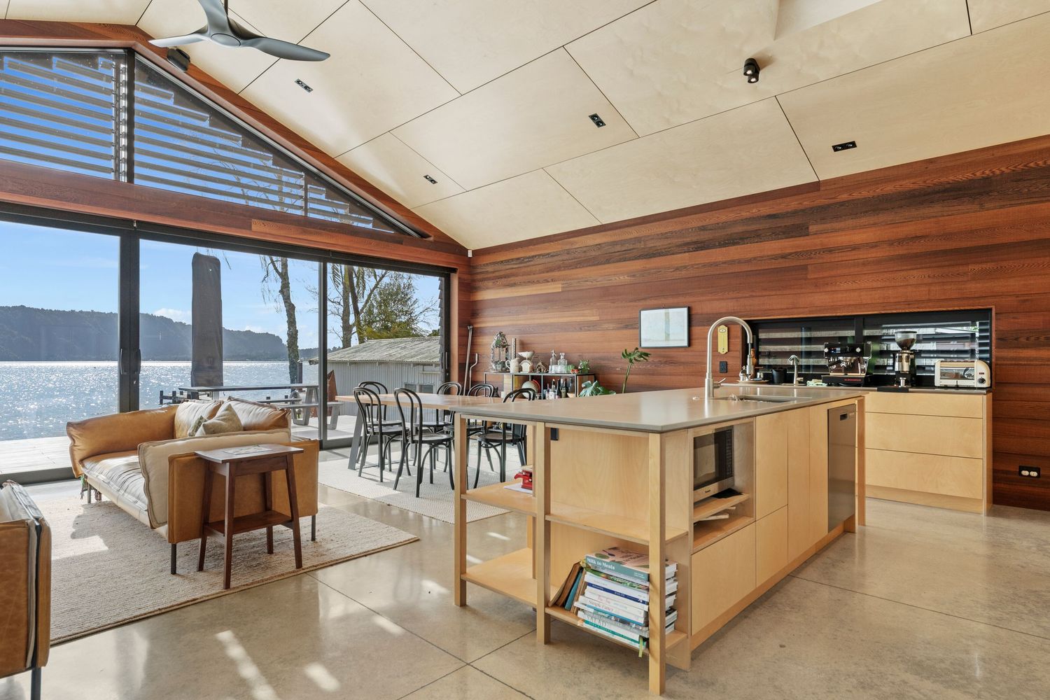 Modern loft living area features warm wood ceiling, sleek railings, and large windows overlooking scenic mountain views.