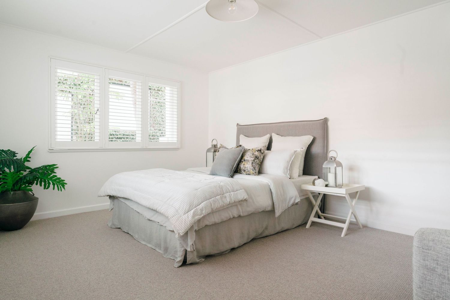 Serene white bedroom with natural light and minimal decor.