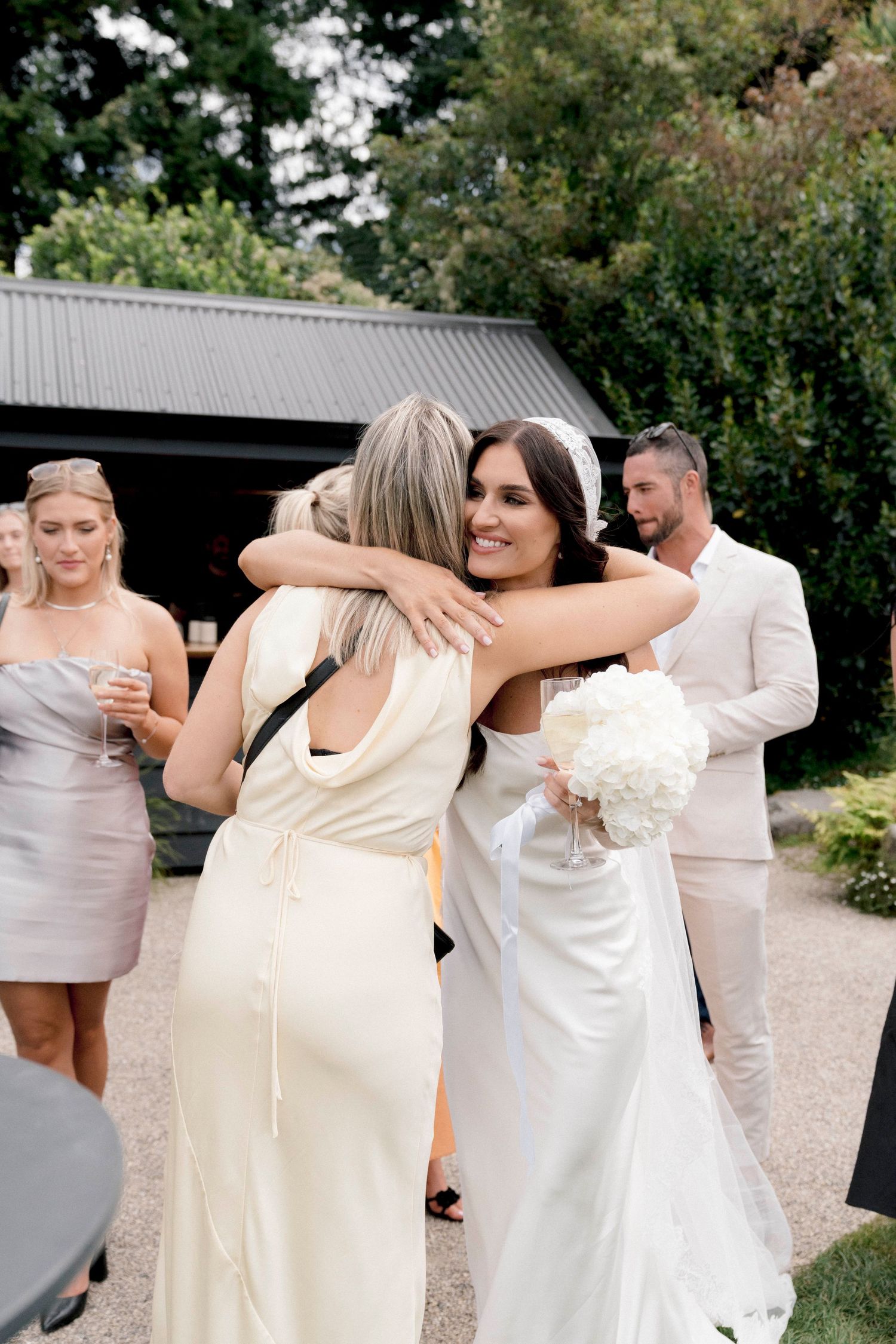 Wedding guests celebrating and embracing outside a modern barn venue.