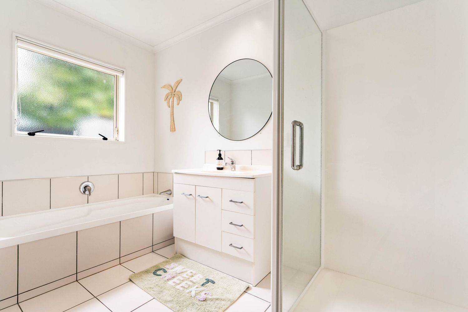 Clean white modern bathroom with built-in vanity cabinets and mirror occupying the full length of the wall.