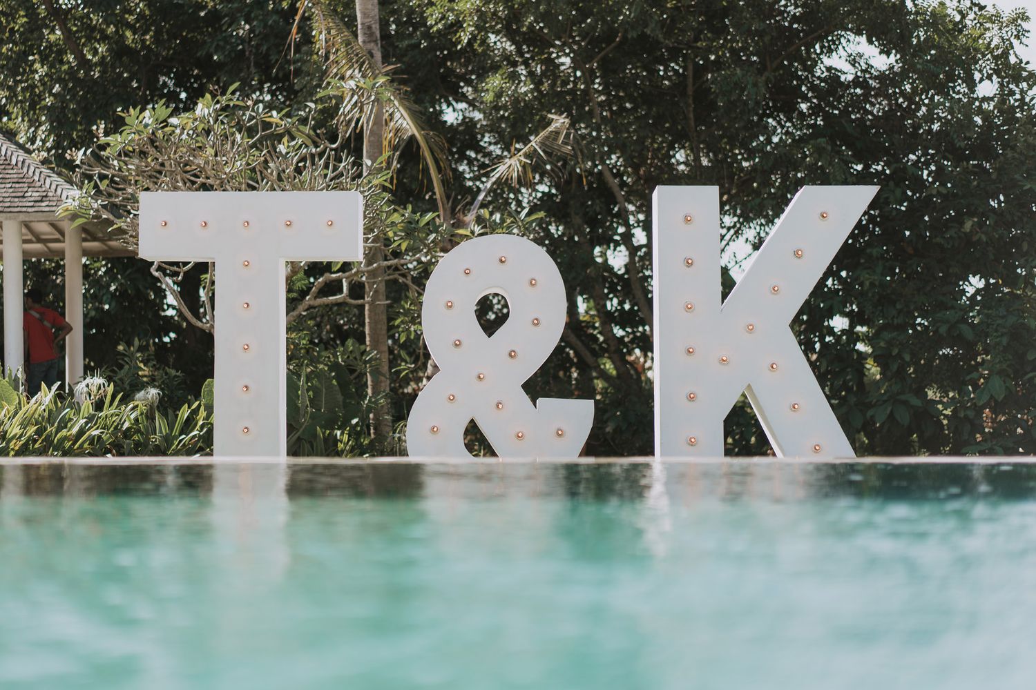 Large white T&K letters displayed near a swimming pool.