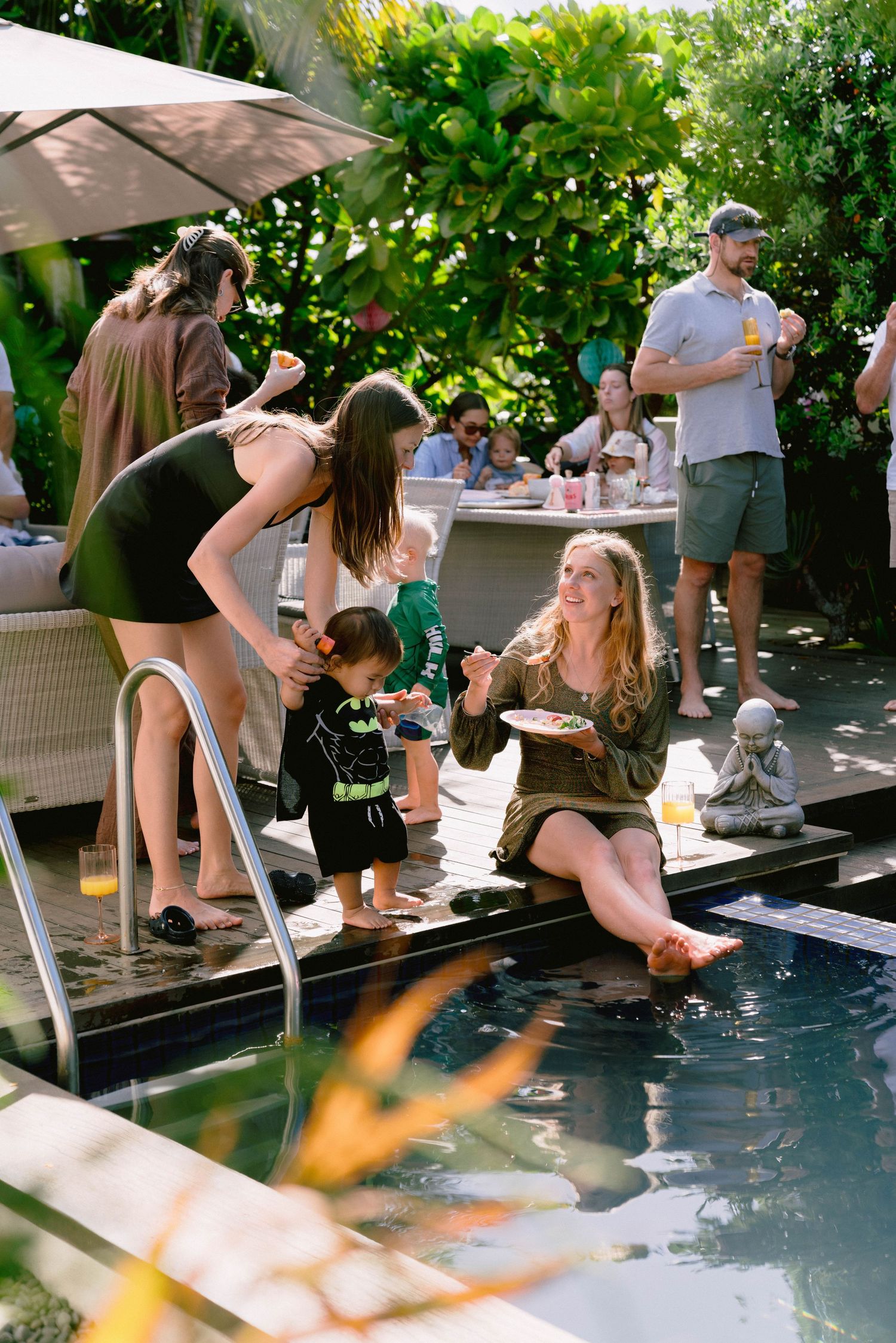 Friends relaxing with their feet in a swimming pool during an outdoor party.