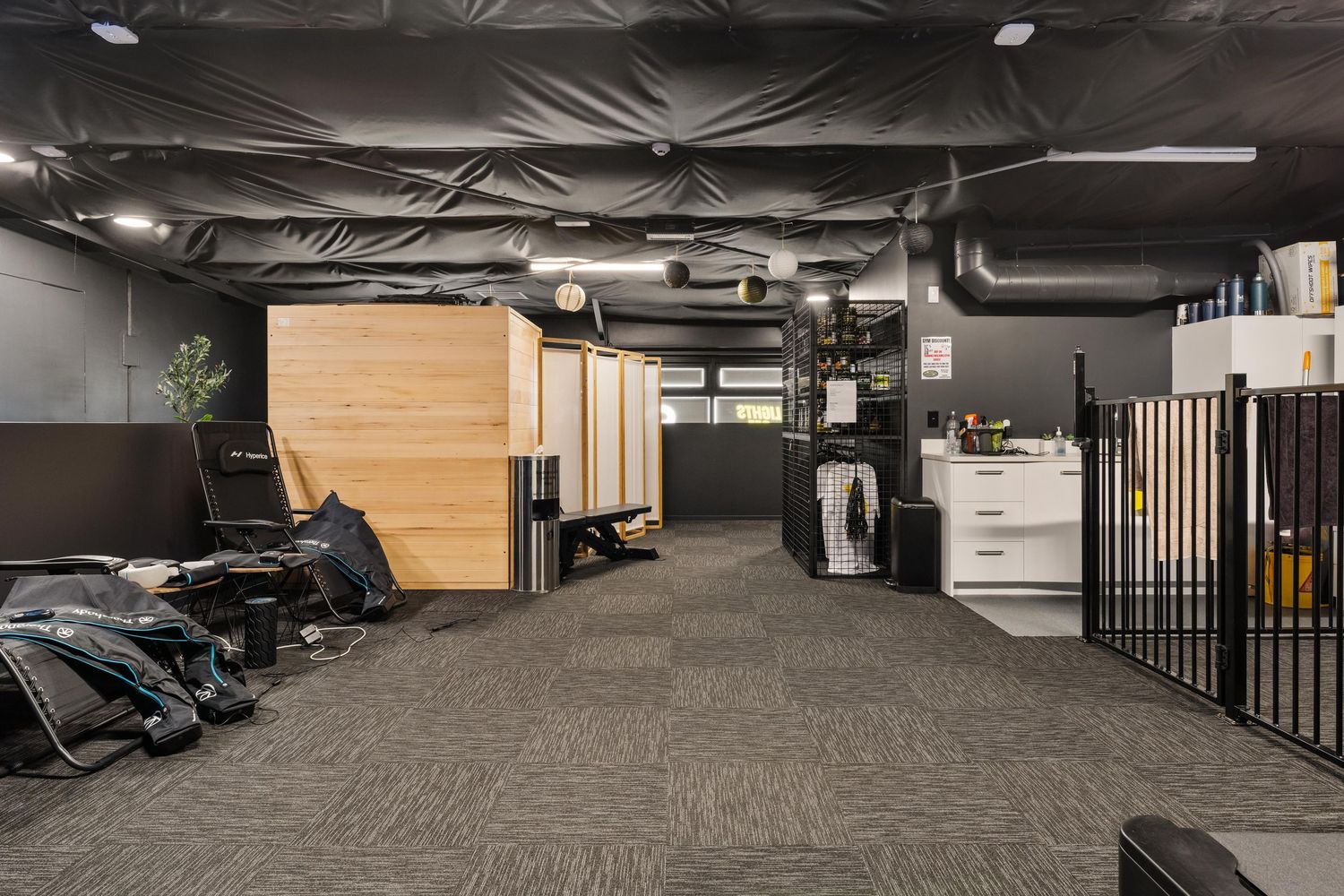Industrial-style gym space with exposed ceiling and carpet flooring.