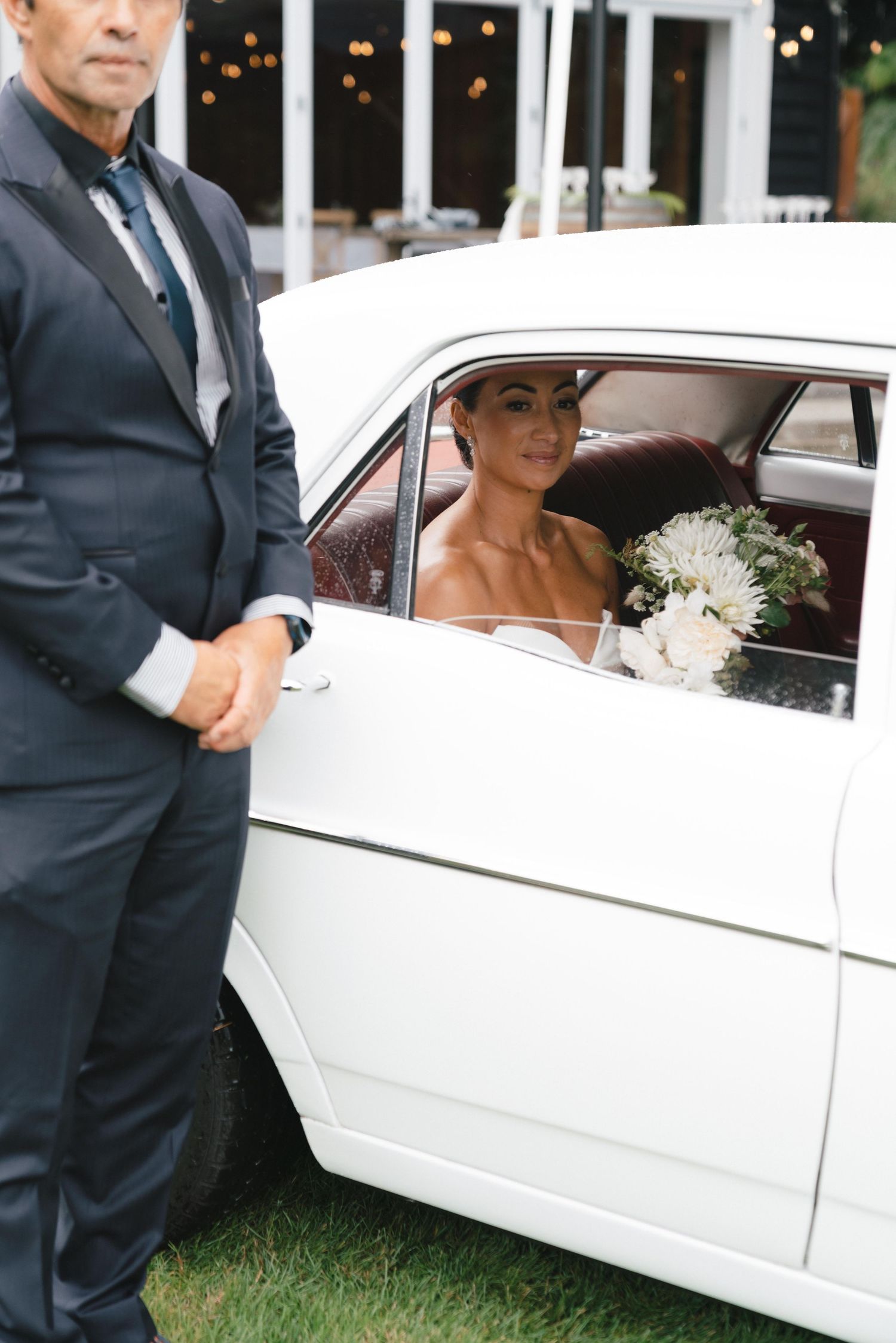 A classic white vintage car with wedding party member arriving at the venue.