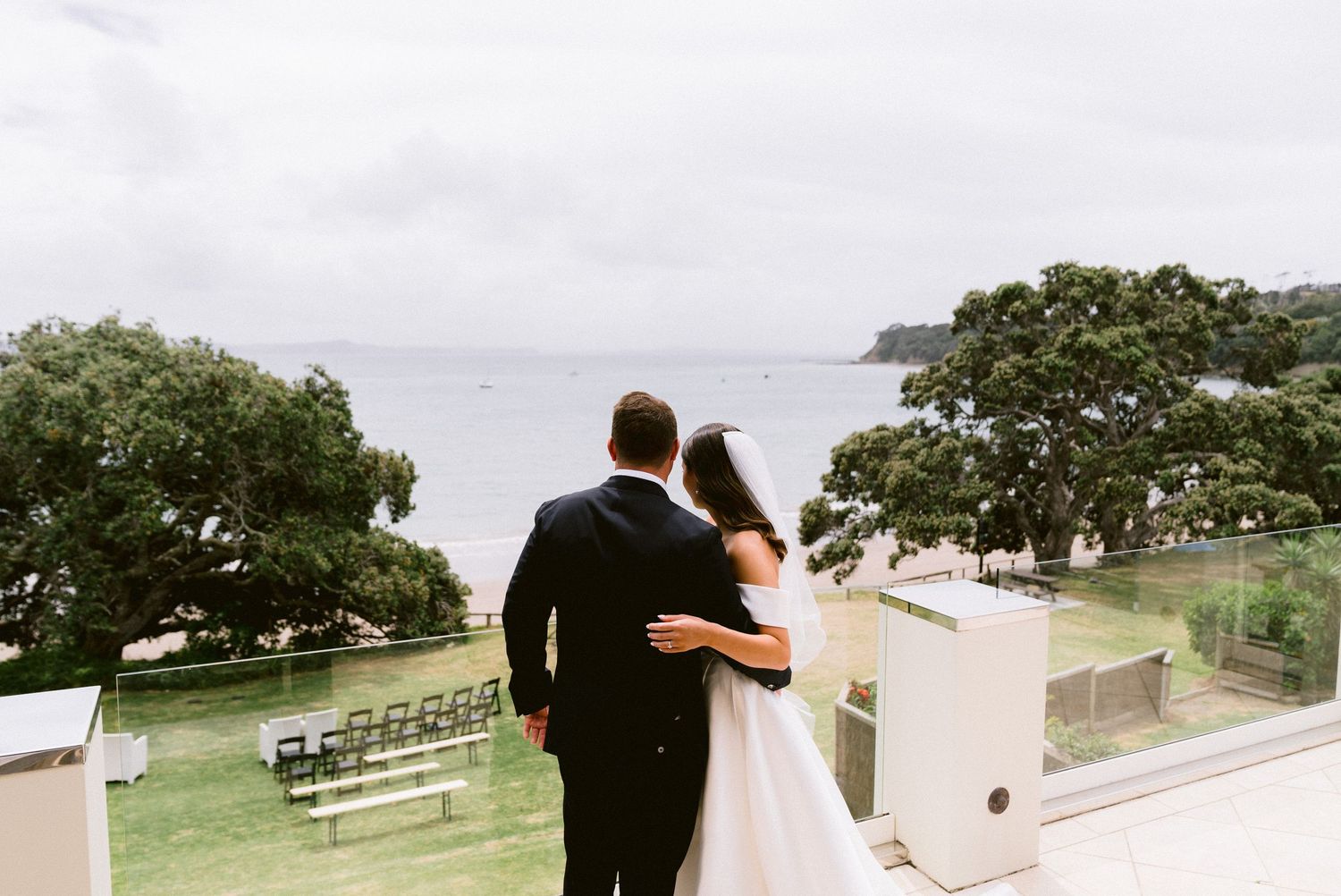 Scenic outdoor wedding venue with white chairs set up for ceremony overlooking the water.