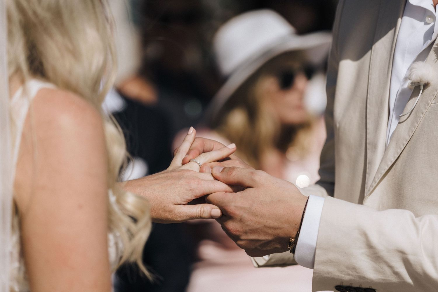 Close up shot of exchanging wedding rings during outdoor ceremony.