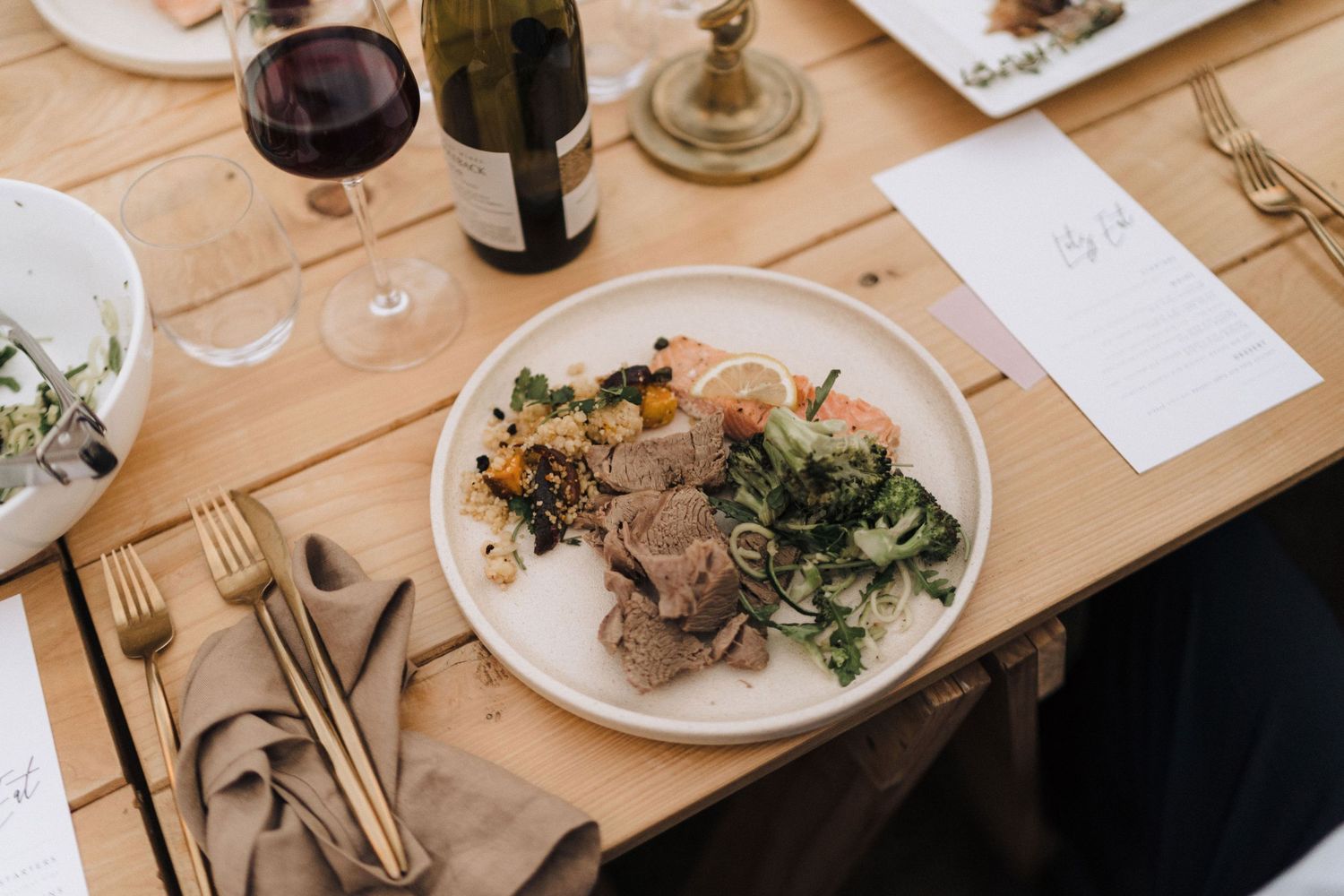 Elegant place setting with wine glass and plated meal at wedding reception.