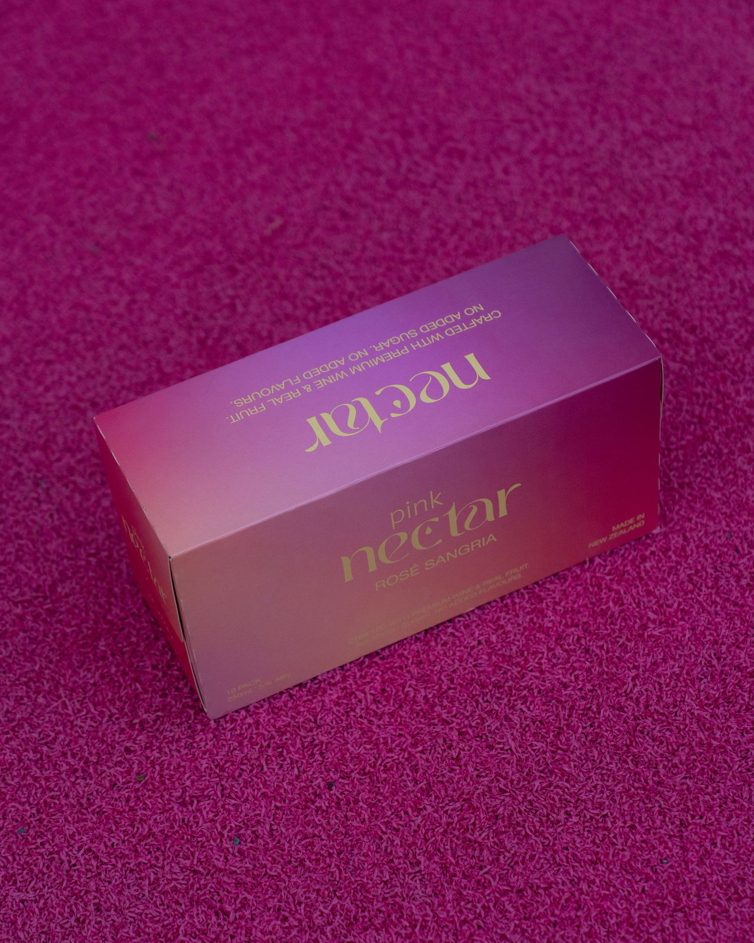 Pink promotional product box for Nectar drink displayed on magenta textured background.