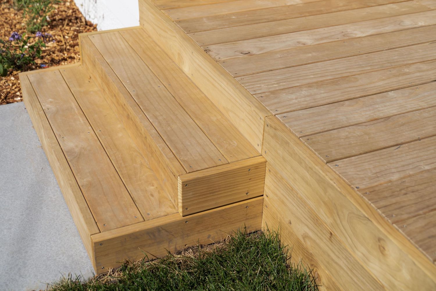 Wooden deck steps with cedar treads and risers arranged in a cascading pattern leading down from a patio.