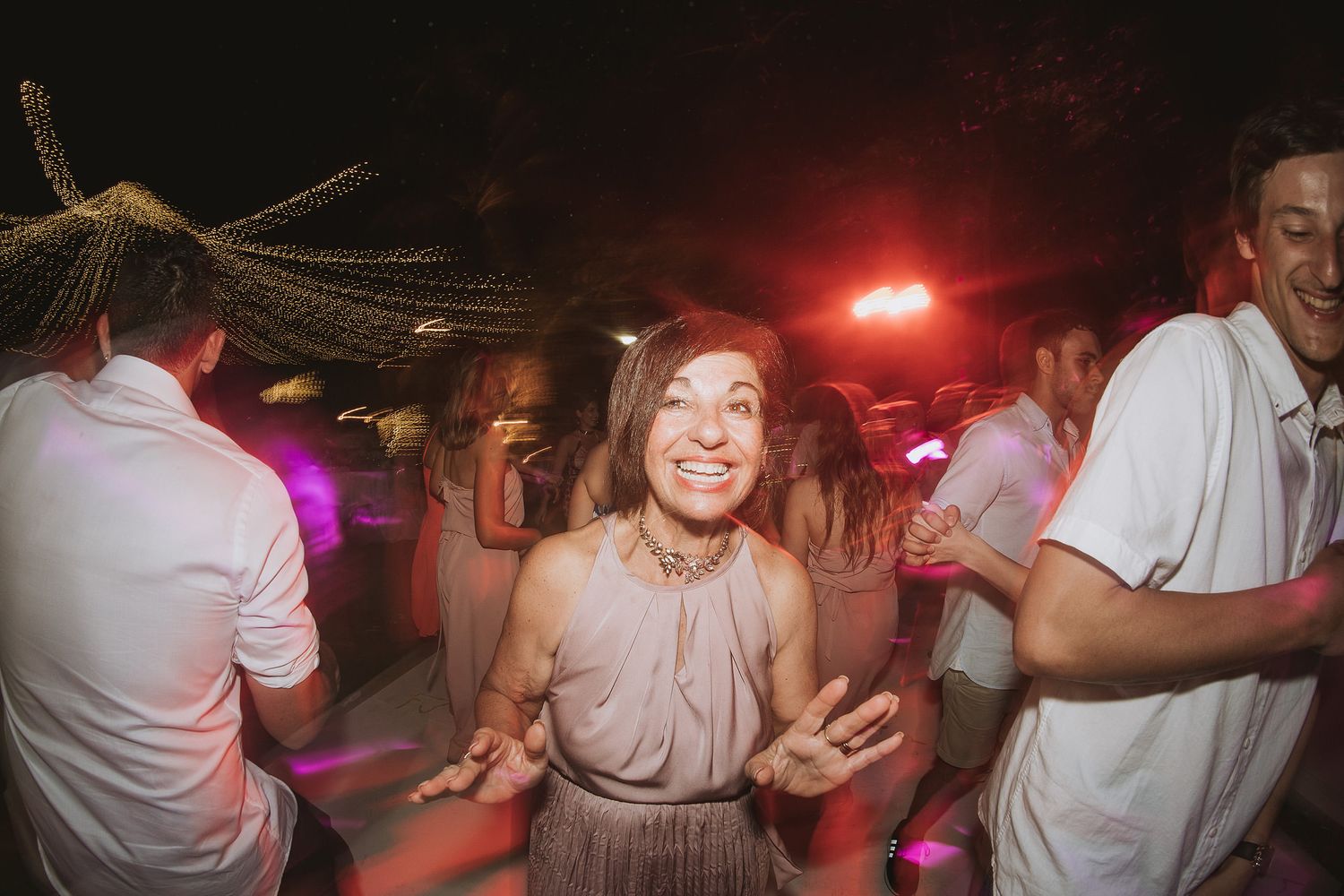 A lively dance party under string lights with guests enjoying the celebration.