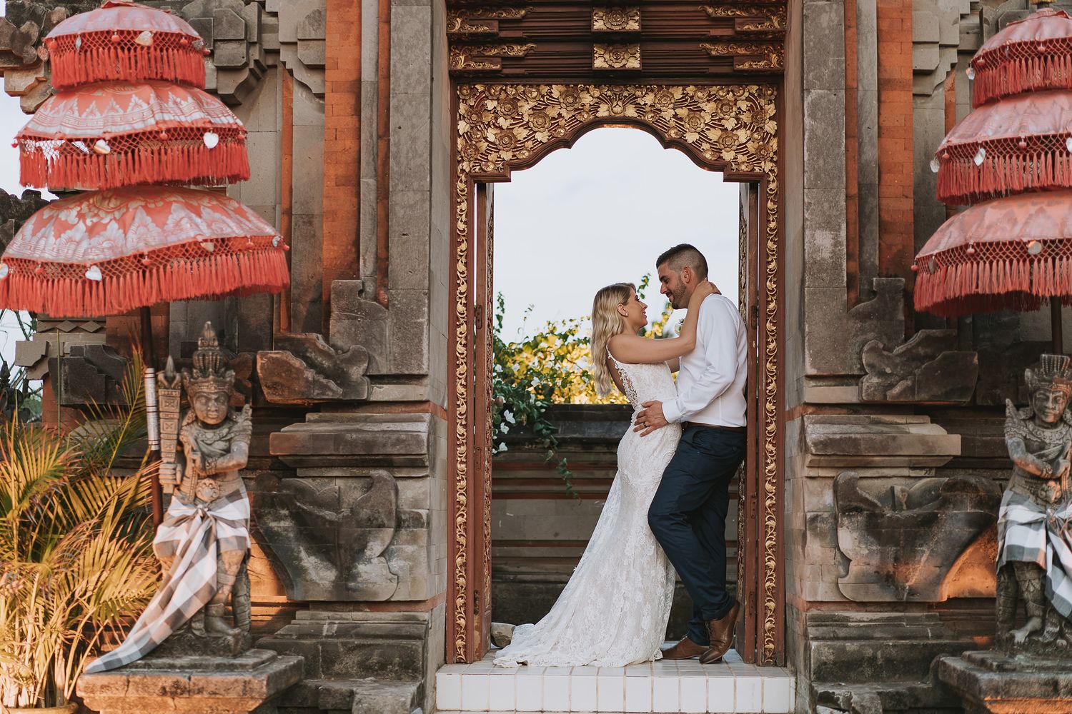 Wedding photo session at a rustic wooden cabin with vintage red umbrella decor.