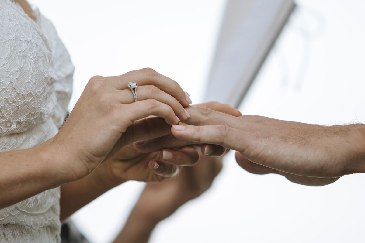 Close-up of hands exchanging a wedding ring during a marriage ceremony with delicate gestures.