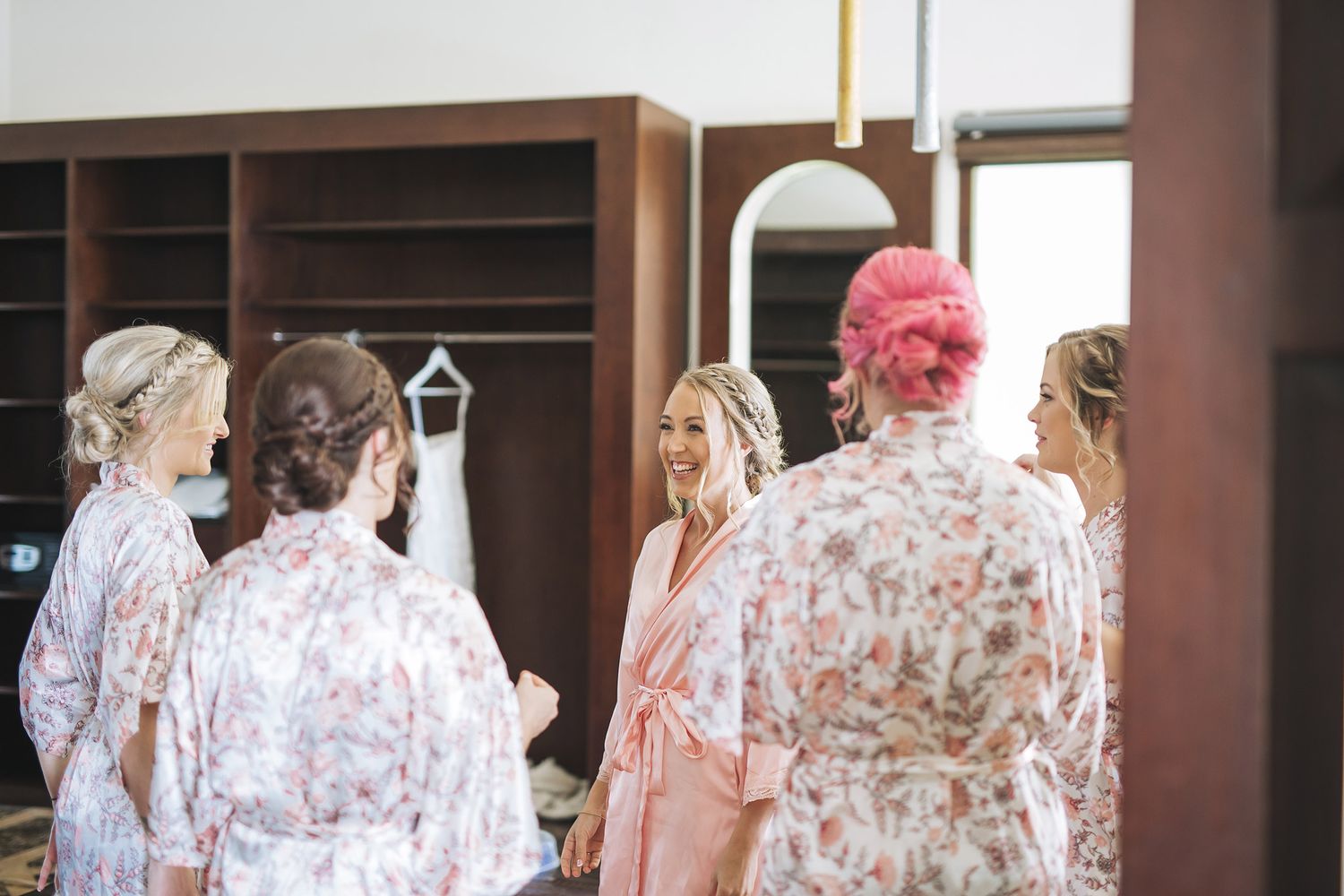 People in floral robes gather in a room with wooden shelving, preparing for a special occasion.