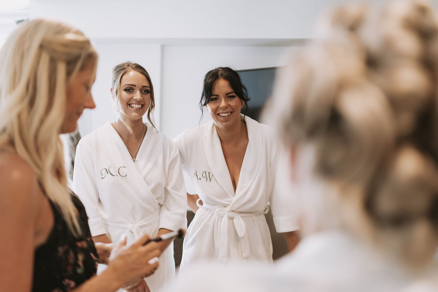 A group of people wearing white robes smile and chat while getting ready for a wedding.