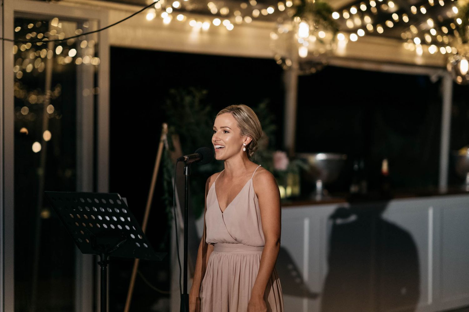 Outdoor wedding venue with string lights illuminating a rustic wooden structure at dusk.