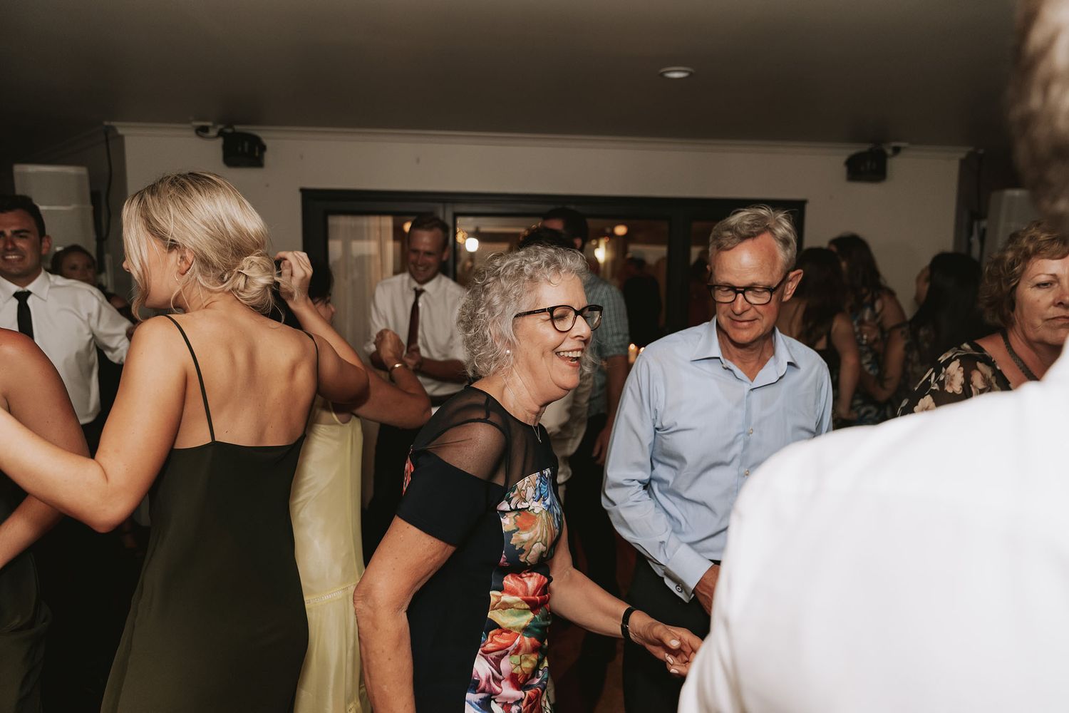 People dancing and mingling at a lively indoor party with low lighting and festive atmosphere.