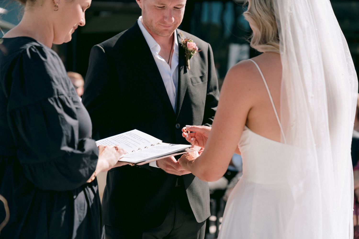 Wedding ceremony moment showing exchange of rings during an intimate outdoor service.