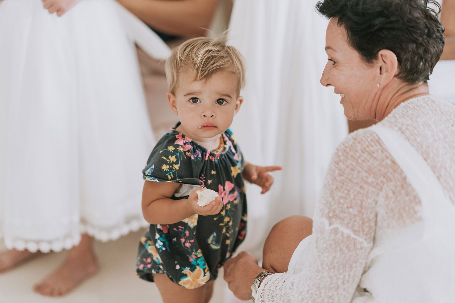 Sweet moment shared between two family members sitting together in a white room with floral pattern clothing.