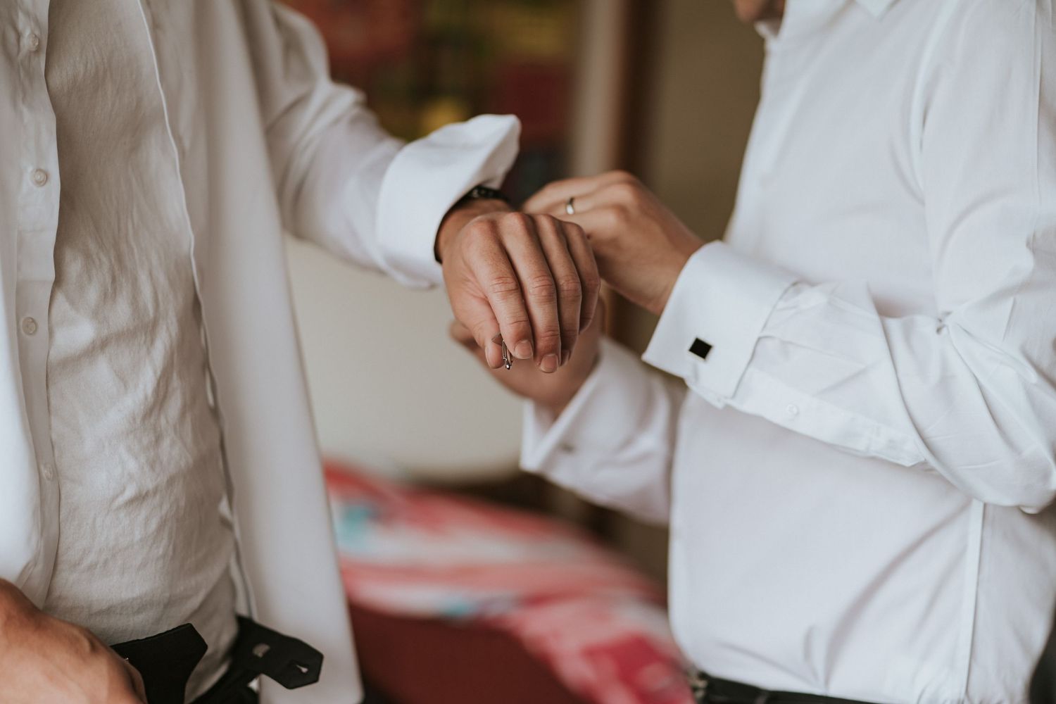 Four people in formal white dress shirts stand in a row with hands in view.