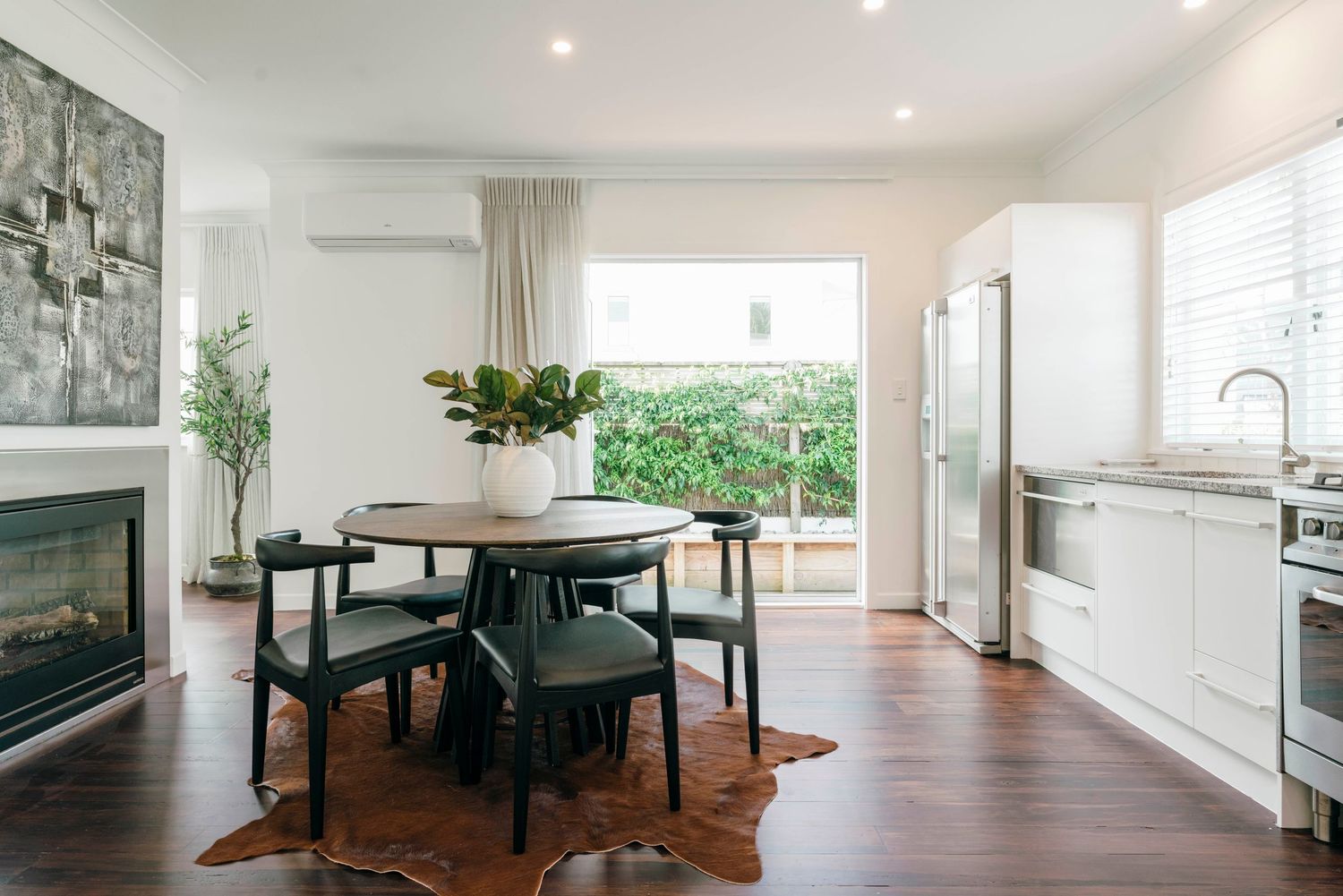 Open plan dining area with black dining set and hardwood floors in modern home.
