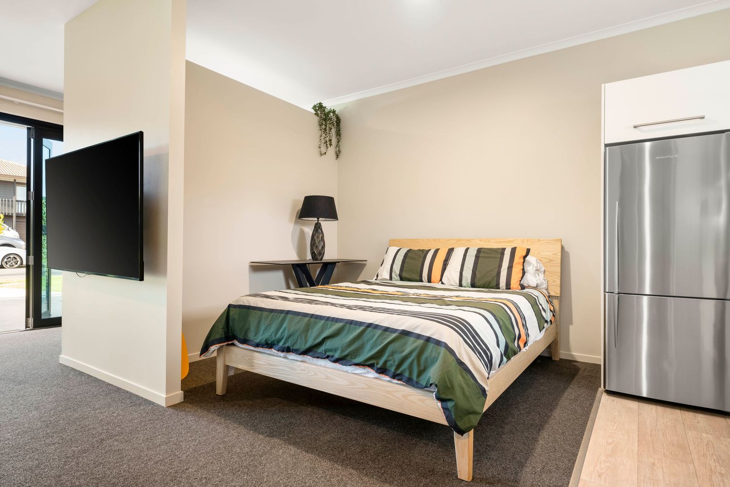 Spacious bedroom with neutral walls, plush bedding, and ample natural lighting from windows.
