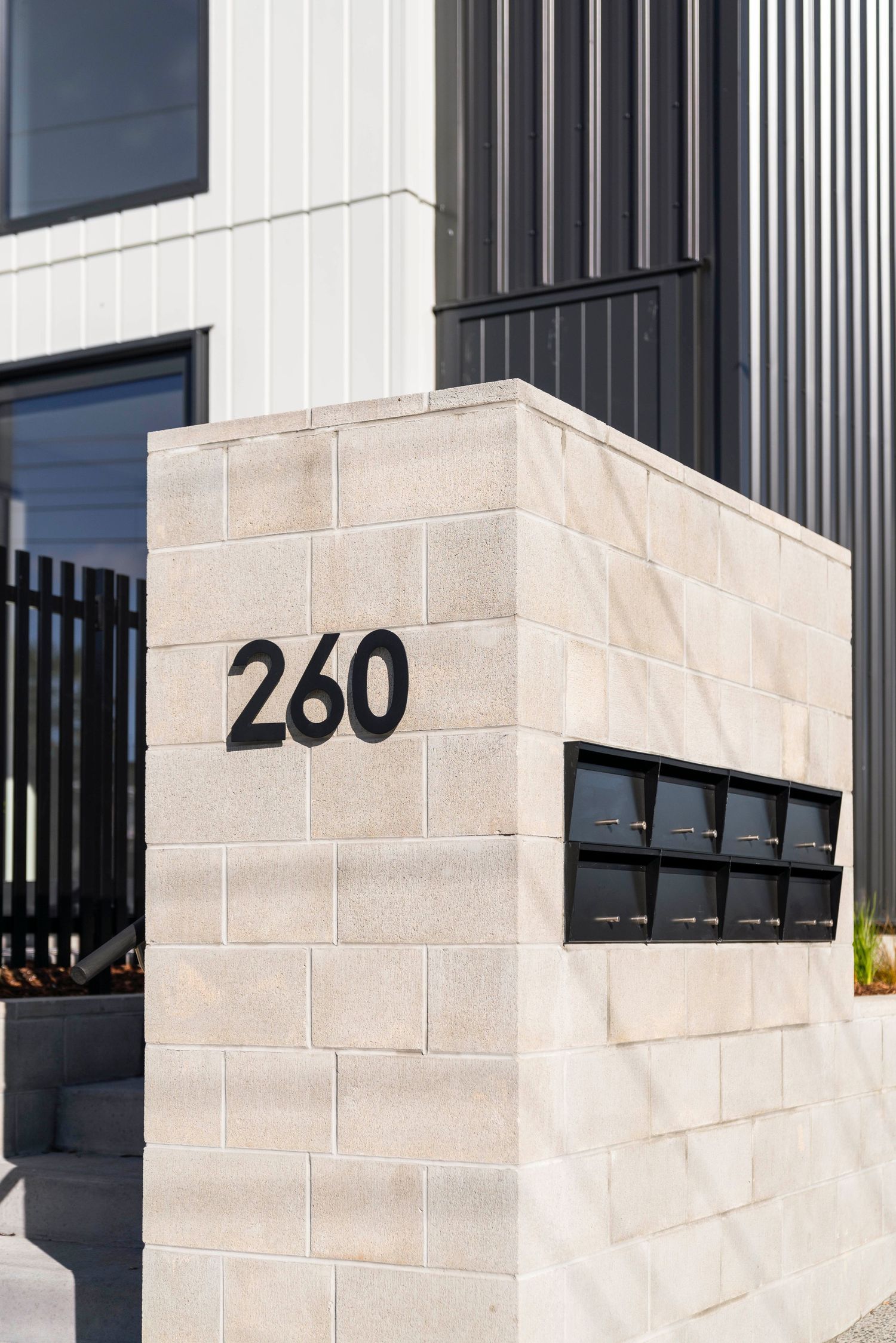 Contemporary building facade with black vertical stripes and white stone blocks featuring number 260.