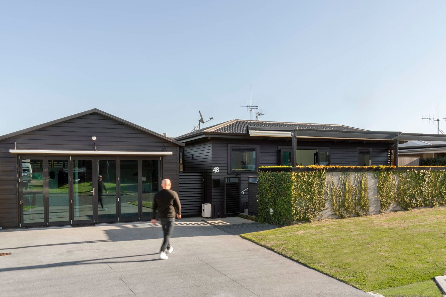A modern single story building with green trim and a well-maintained lawn in the foreground.