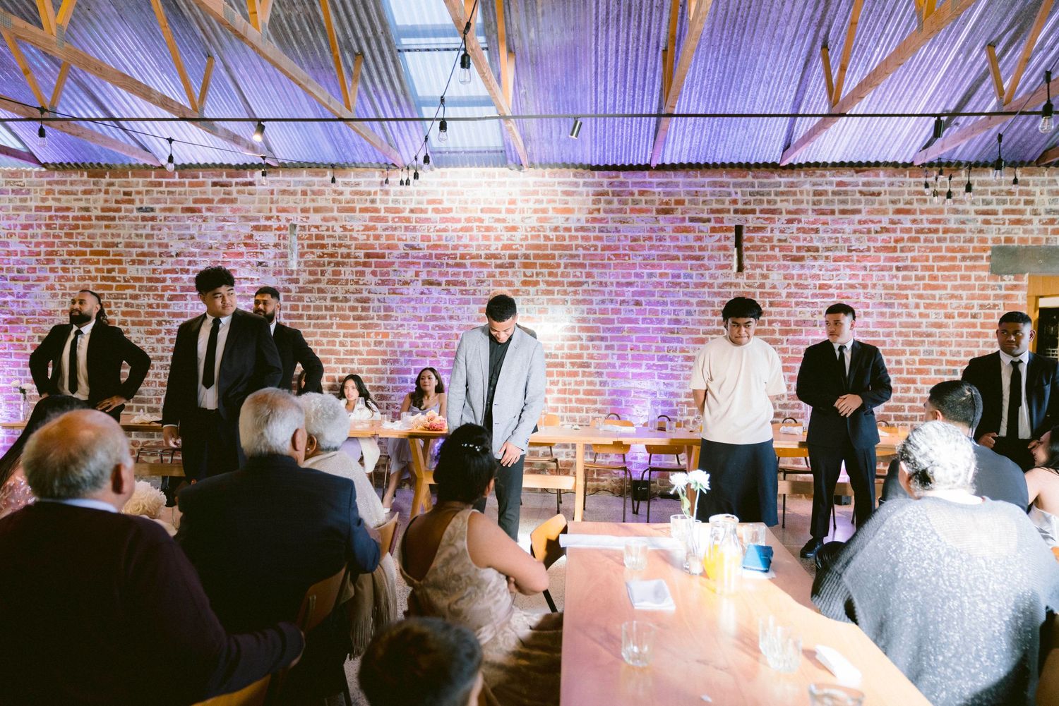 Wedding reception venue interior showing brick walls and industrial style lighting with guests mingling.