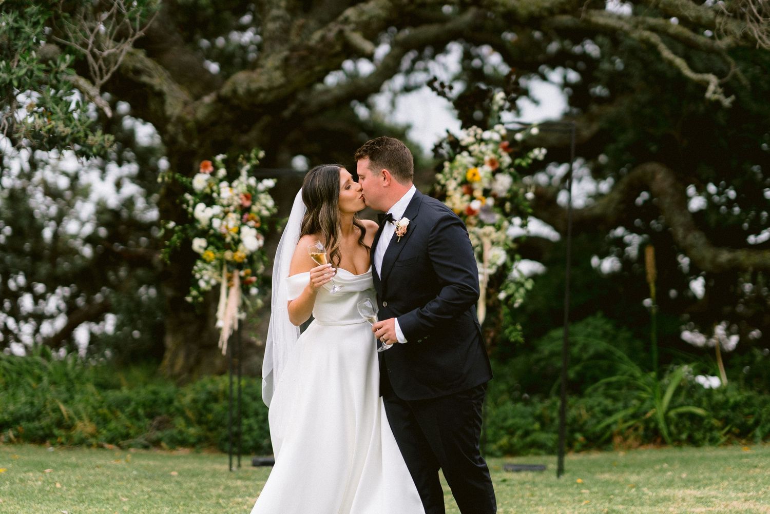 Wedding celebration in a lush garden setting with elegant floral decorations and formal attire.