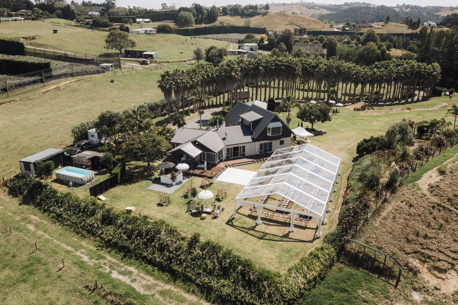 Aerial view of a modern wedding venue with marquee tent and landscaped grounds in rural setting.